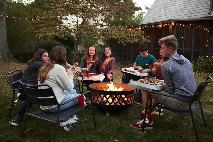 Group of people enjoying and evening in the garden around a fire pit