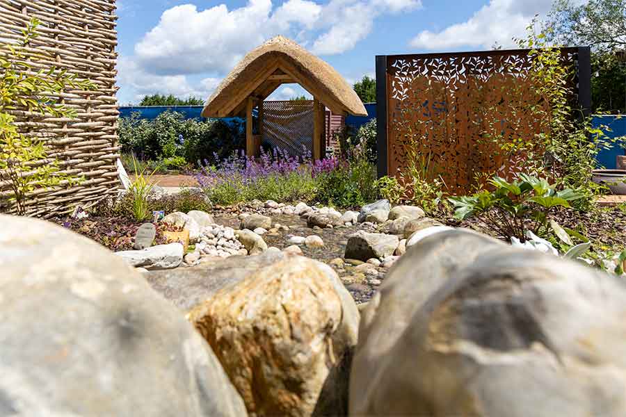 Thatched gazebo at the bottom of a water feature in the Oxford Garden Centre Feature Garden